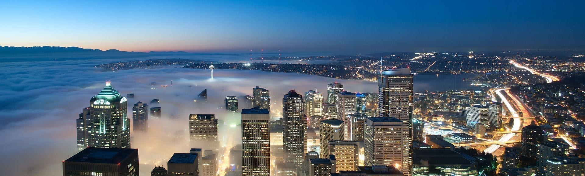 A nighttime view of downtown Seattle with its high-raise buildings partially obscured by fog