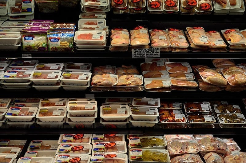 A selection of packaged, processed meat products in a grocer's refrigerated meat case.