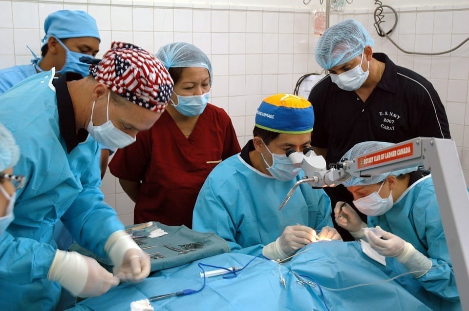 A group of doctors operates on a patient in a hospital setting.