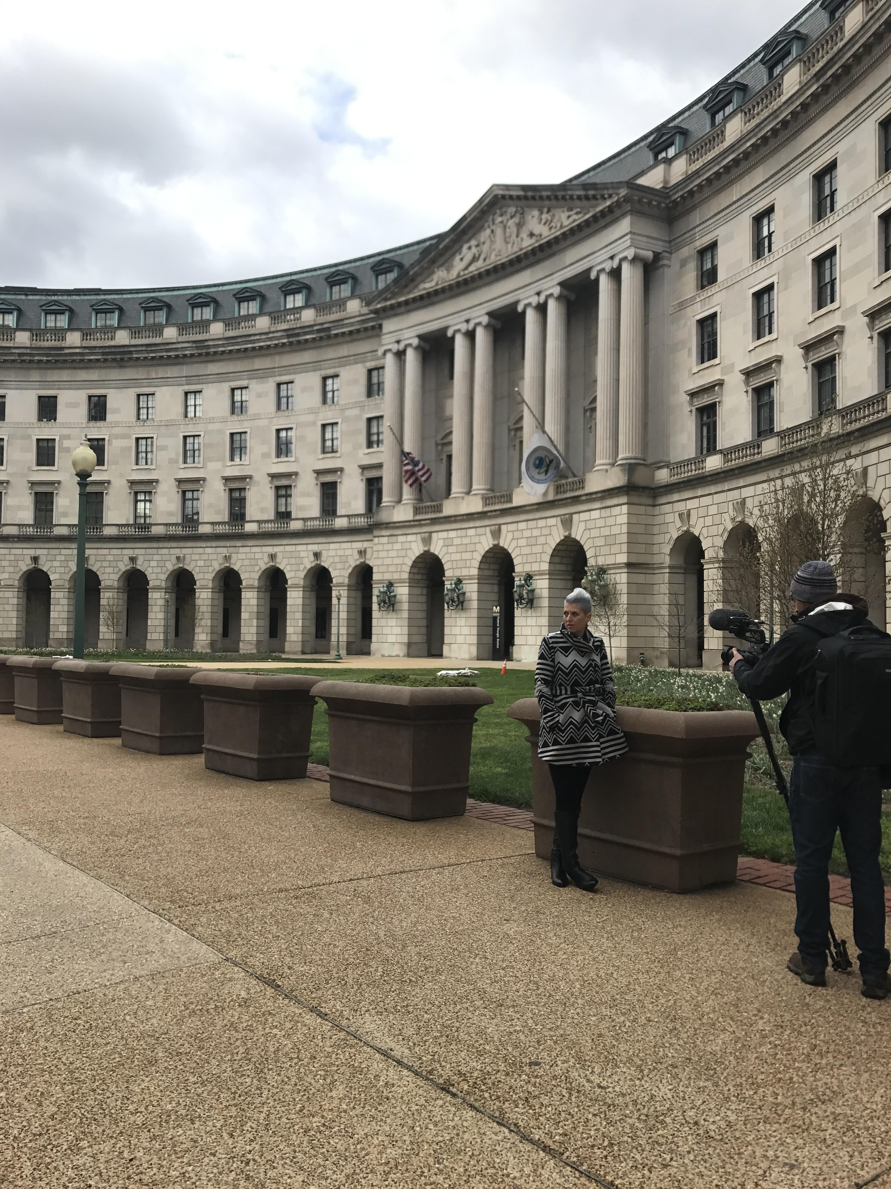 Heather Von St. James stands outside the EPA building in Washington, D.C., with a photographer in the foreground.
