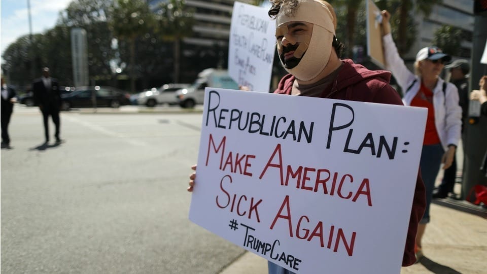Man holding a sign saying Republican Plan - Make America Sick Again