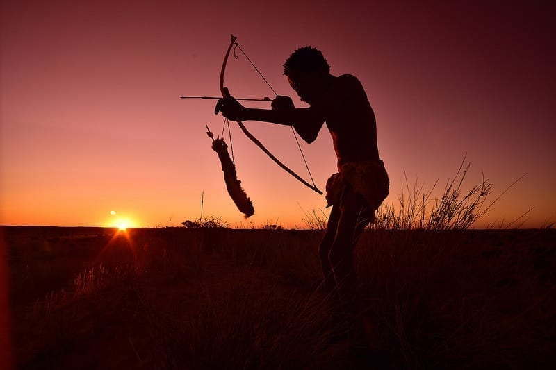 A Kalahari Bushman with bow and arrow, at sunset.