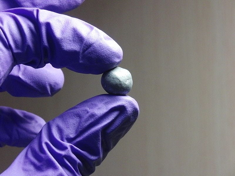 A blue-gloved hand holding a ball of valuable, toxic beryllium.