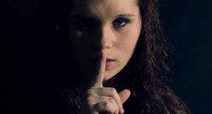 A woman holds her finger to her lips in the classic Shhhh position.