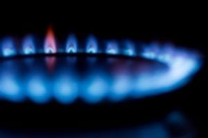 Blue flames from a natural gas burner form a ring in the dark.