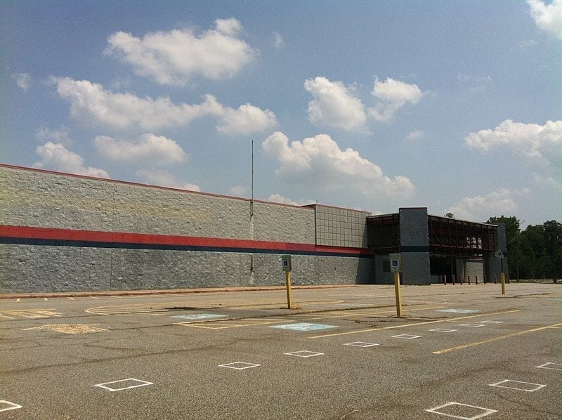 An abandoned Walmart, what's known as a dark store, falls apart in an empty parking lot.
