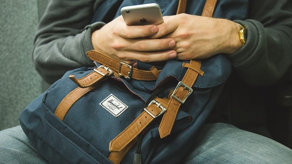 A traveler with a backpack using a smartphone.