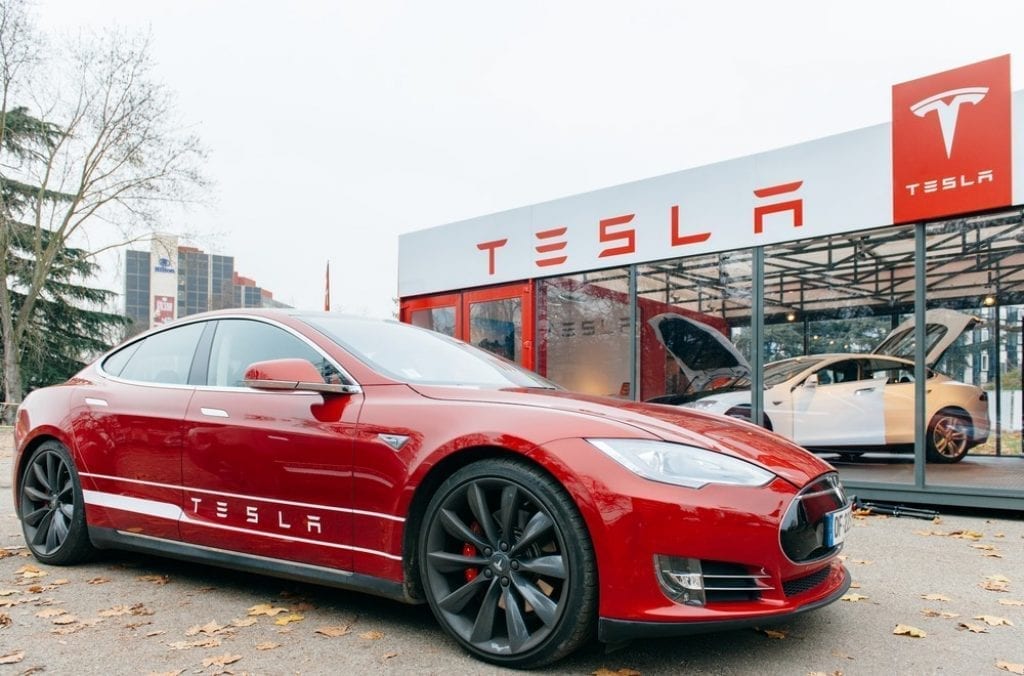Electric car parked in front of Tesla dealership; image courtesy of www.dailyreckoning.com.au.