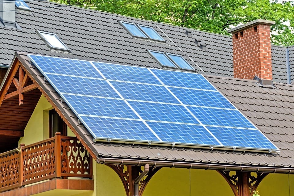 Rooftop solar panels adorn a house with intricate wooden trim.