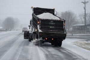 A salt truck seasons a snow-covered road to prevent ice buildup and keep drivers safe.