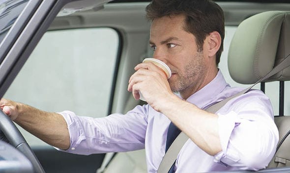 Man drinking coffee while driving; image courtesy of www.express.co.uk.