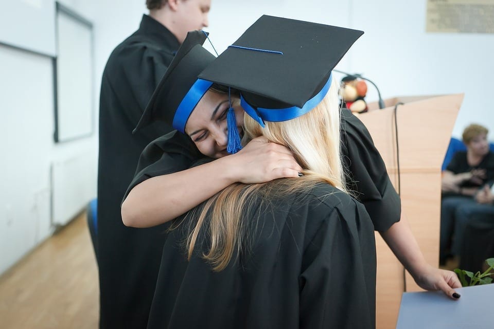 Image of two college grads embracing