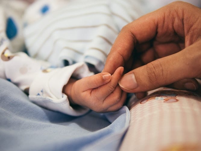 Image of a Newborn and Mother Holding Hands