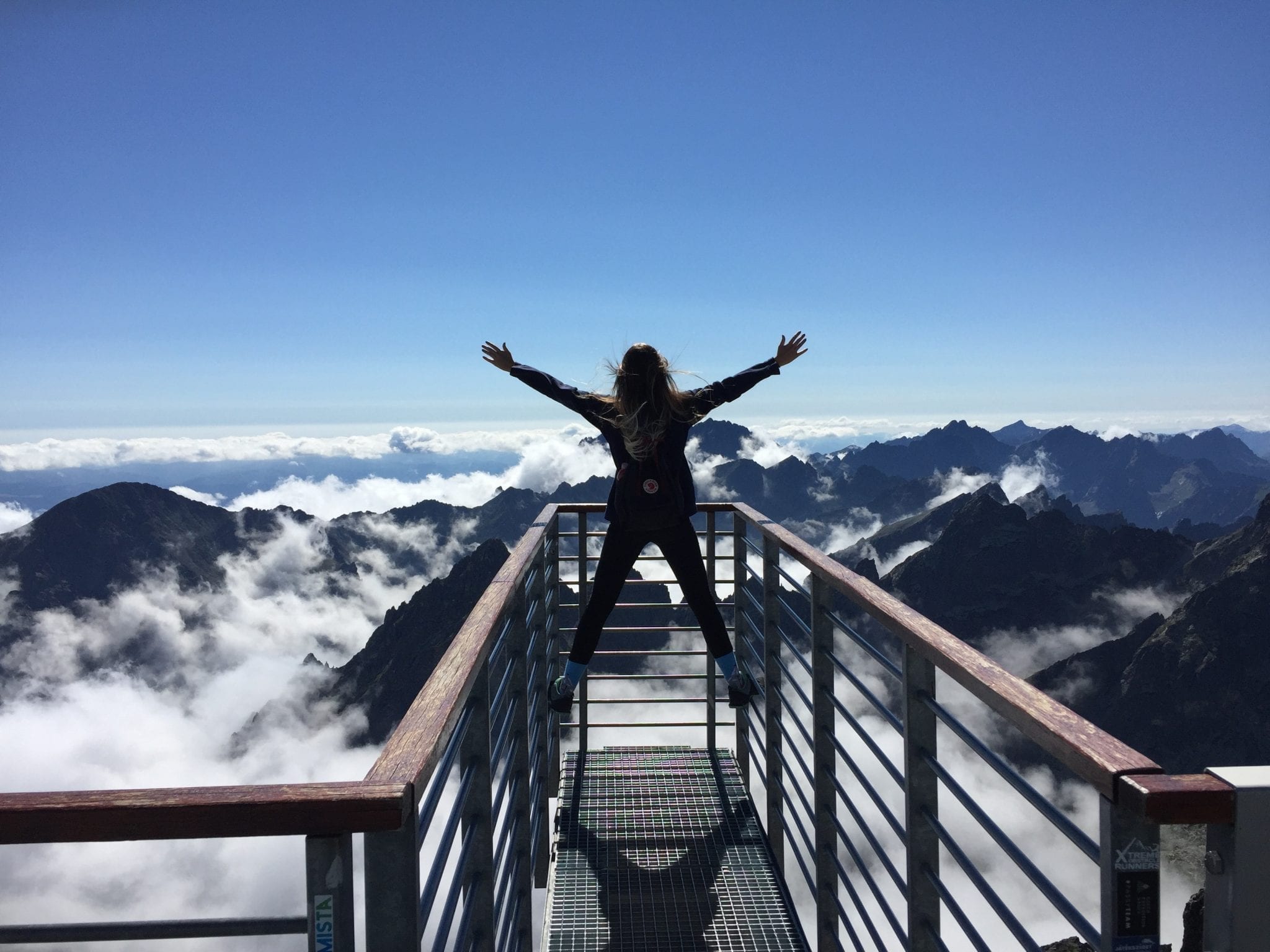 Overcoming challenges – woman overlooking mountains; image by Nina Uhlíková, via Pexels.com, CC0.