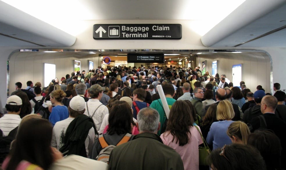 An airport hallway chock full of people heading to the baggage claim area.
