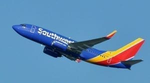 A blue, orange and red Southwest Airlines airplane takes off into a cloudless sky.