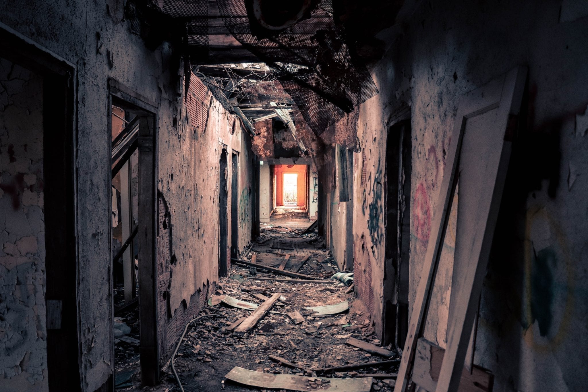 A decrepit, falling-apart hallways leads to an uncertain light.