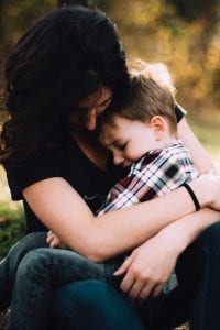 Woman hugging upset little boy; image by Jordan Whitt, via Unsplash.com.