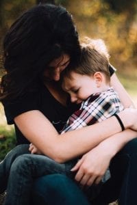 Woman hugging upset little boy; image by Jordan Whitt, via Unsplash.com.