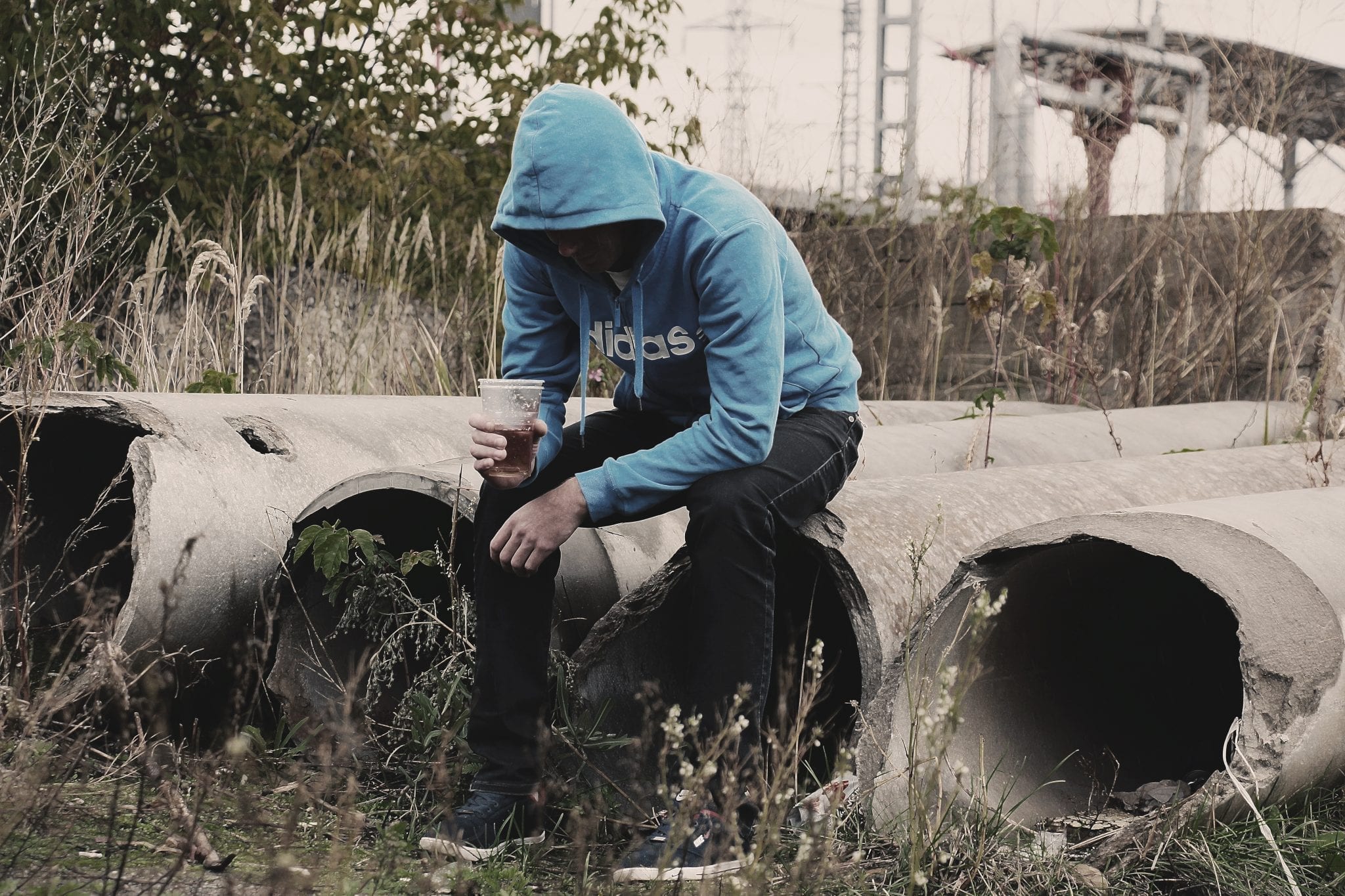 Man sitting alone in abandoned area; image via Pxhere, CC0.