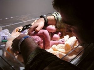 Image of a Baby on warming tray attended to by her father