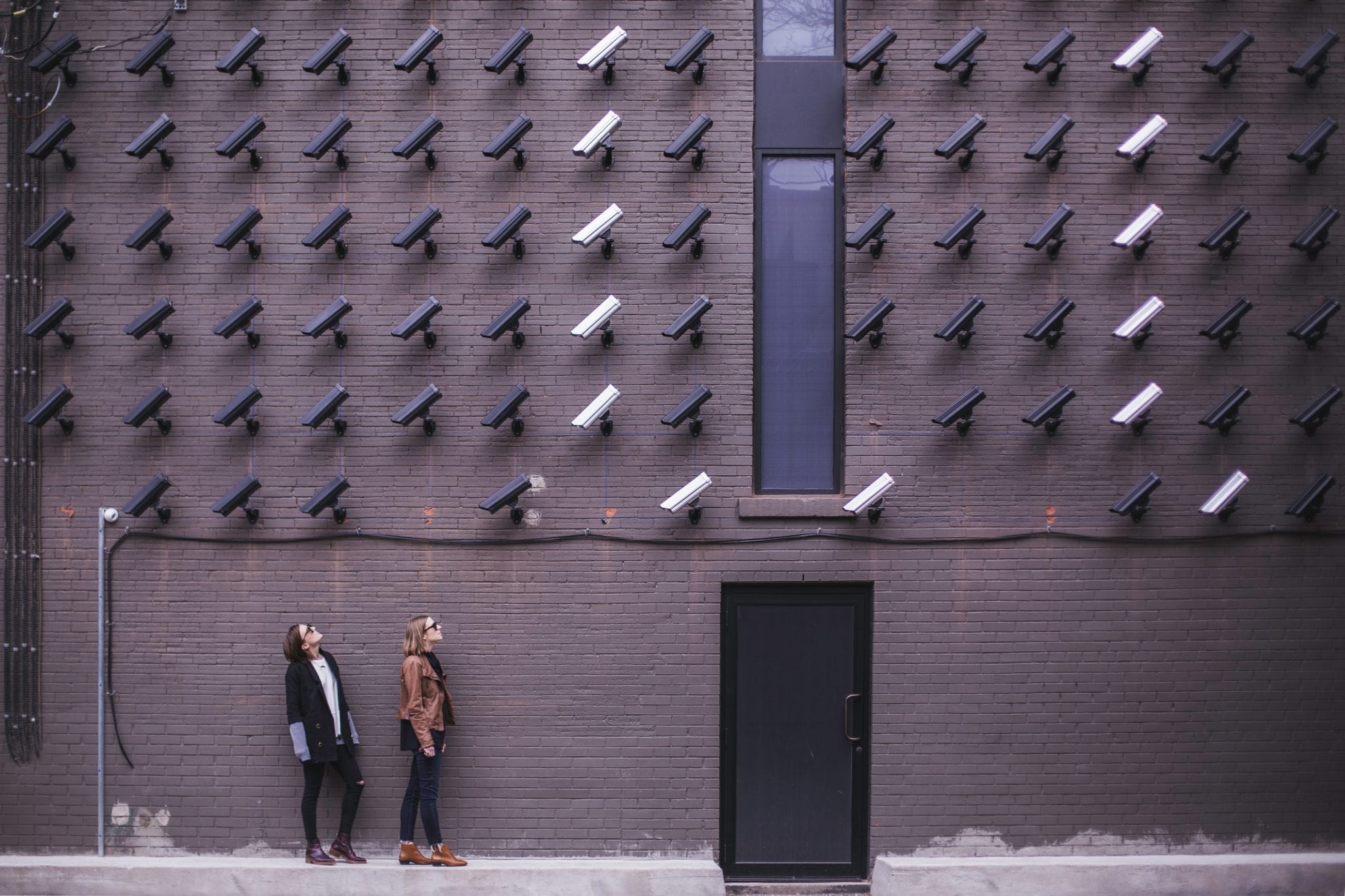 Multiple cameras tracking two women outside a building; image by matthew henry 87142 via unsplash.