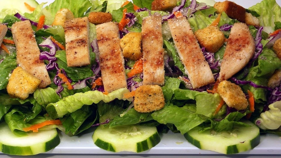 Image of cooked chicken ontop of a salad