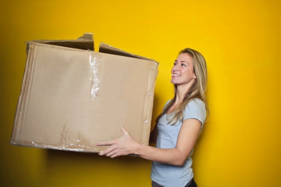 Woman carrying box; image by Bruce Mars, via Pexels.com.