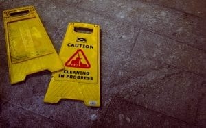 “Caution: Cleaning in Progress” signs lying on tile floor; image by Oliver Hale, via Unsplash.com.