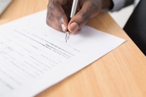 Man signing paperwork with a fountain pen; image by Cytonn Photography, via Unsplash.com.