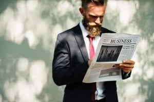 Man reading business section of newspaper; image by Rawpixel, via Unsplash.com.