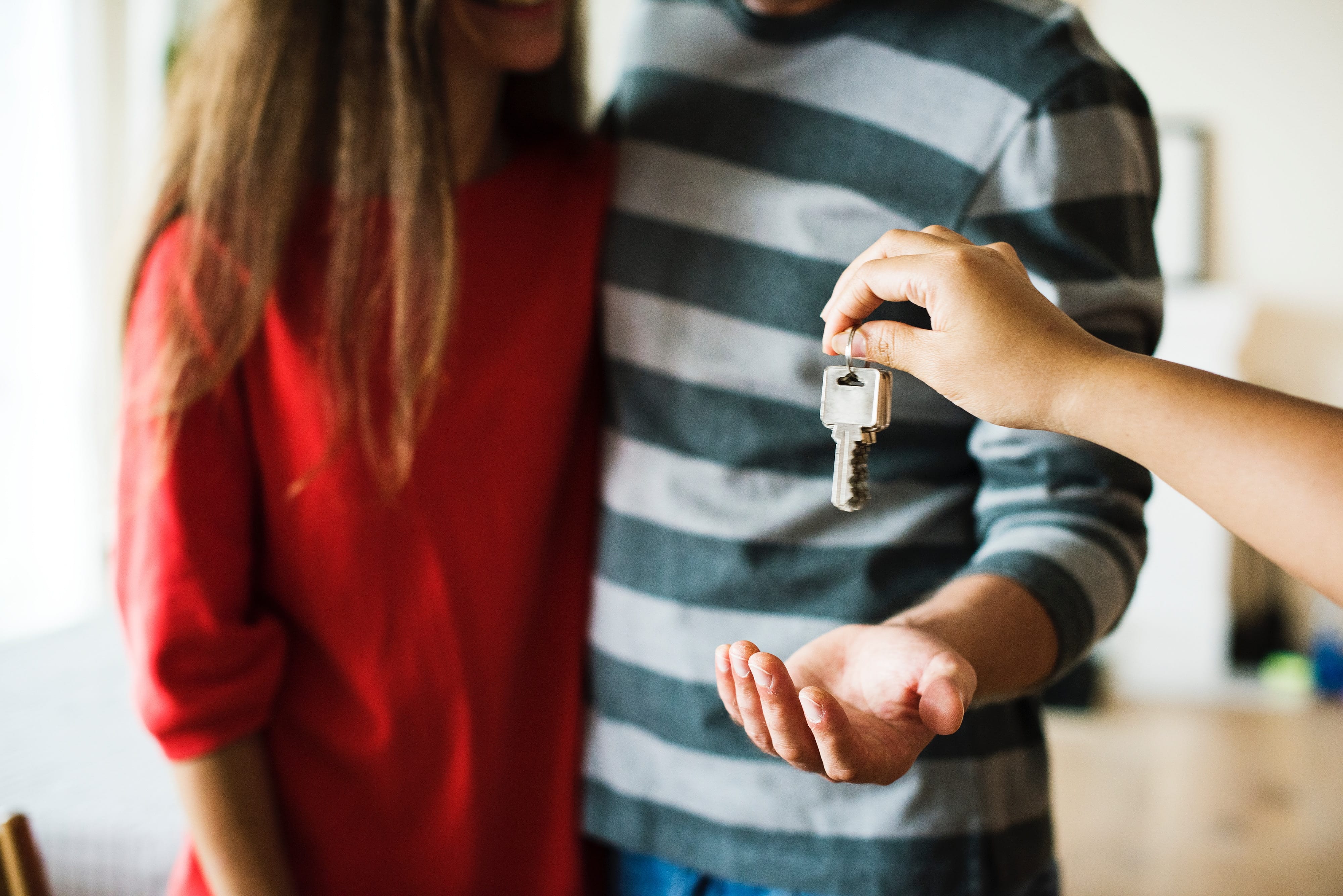 Man and woman being handed keys to a new home; image by Rawpixel, via Unsplash.com.