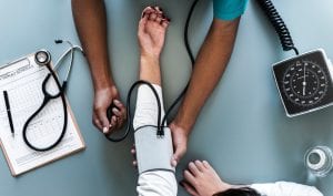 Woman having blood pressure taken; image by Rawpixel, via Unsplash.com.