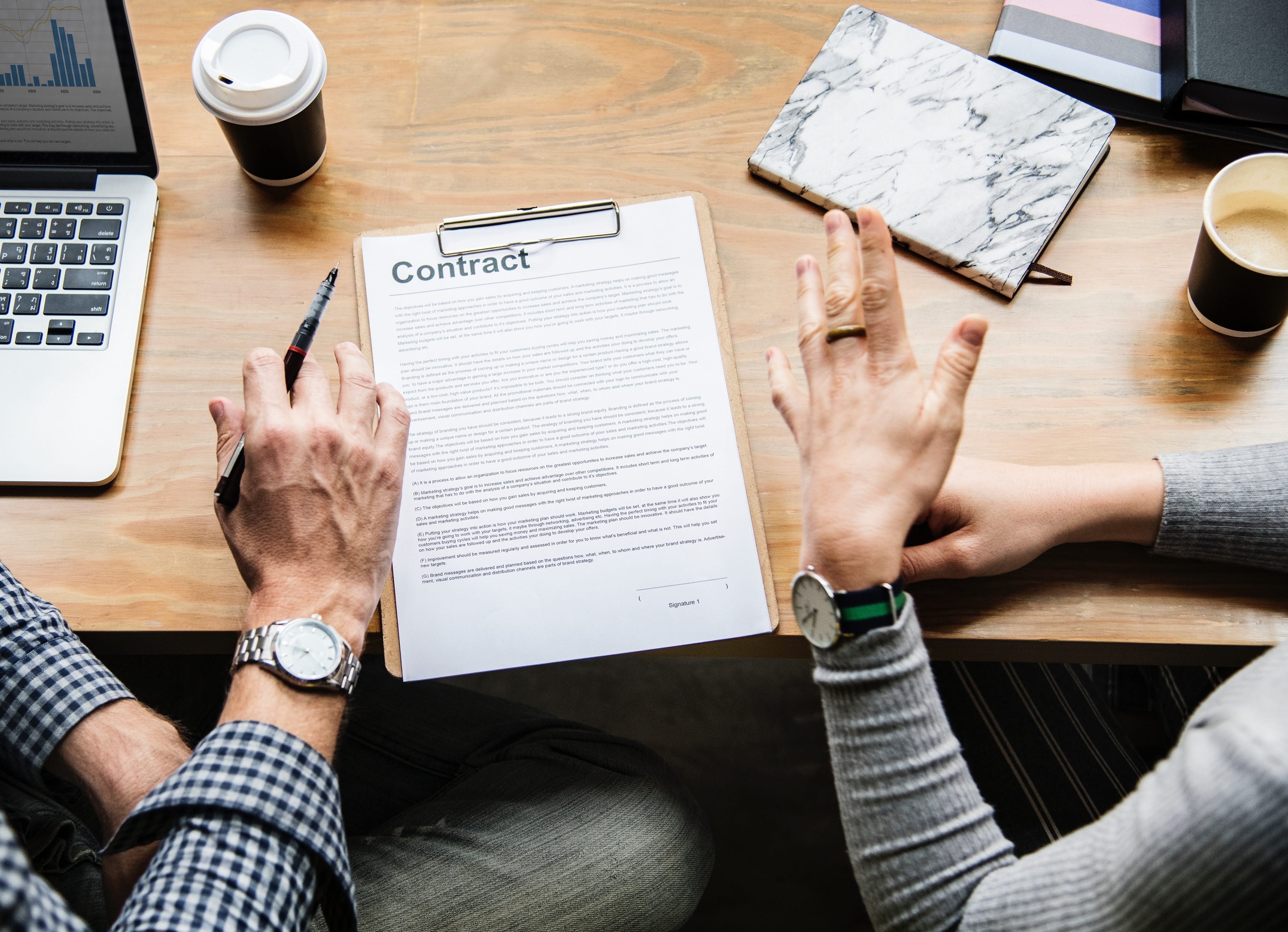 Two people reviewing a contract; image by Rawpixel, via Unsplash.com.