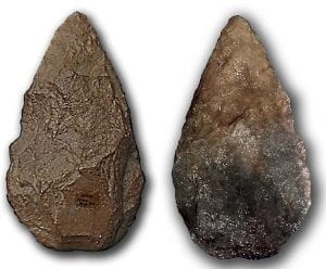 A close up view of the front and back of a stone hand axe, against a white background.