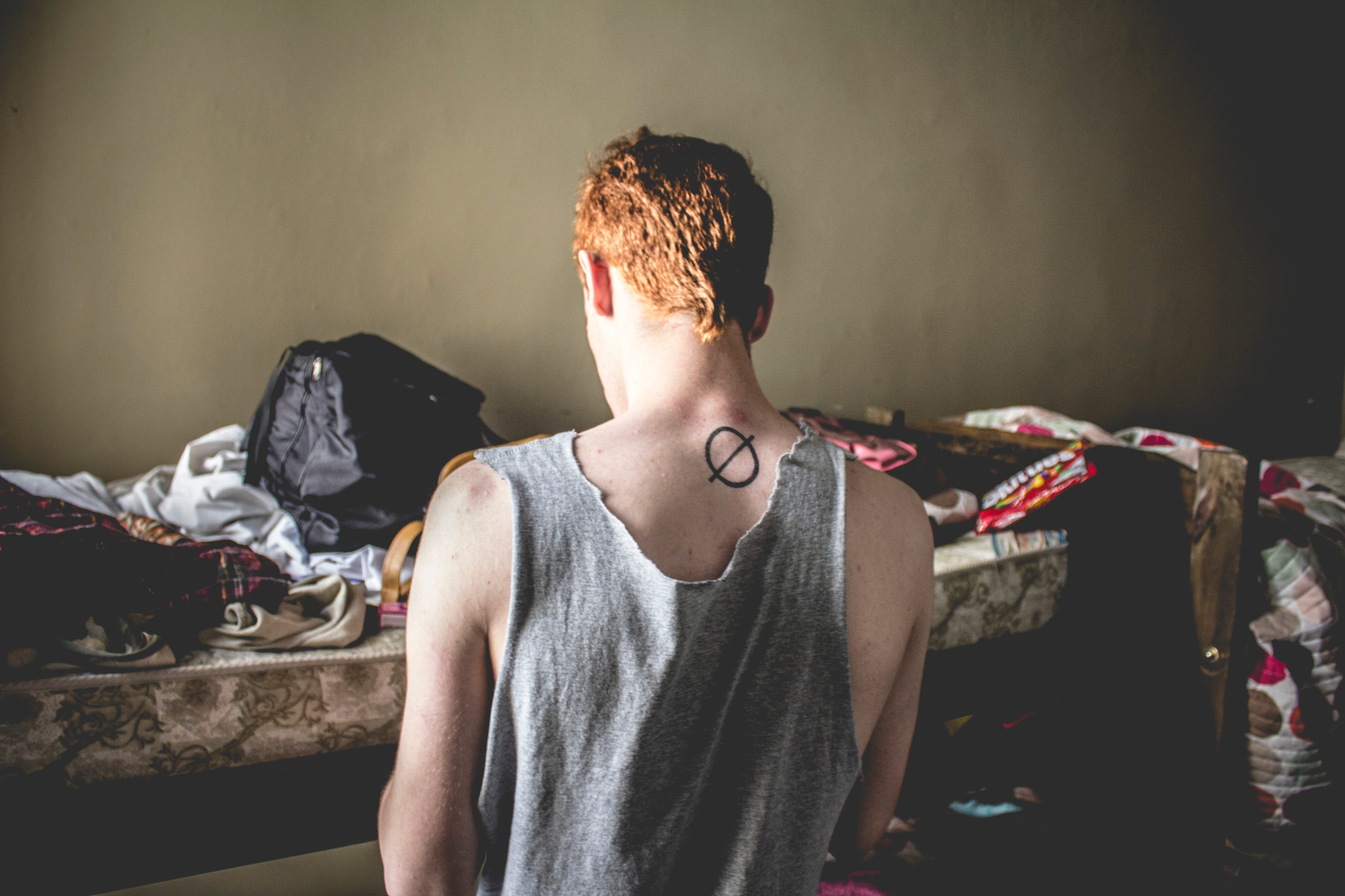 Red-haired man kneeling in cluttered bedroom; image by Greta Schölderle Møller, via unsplash.com.