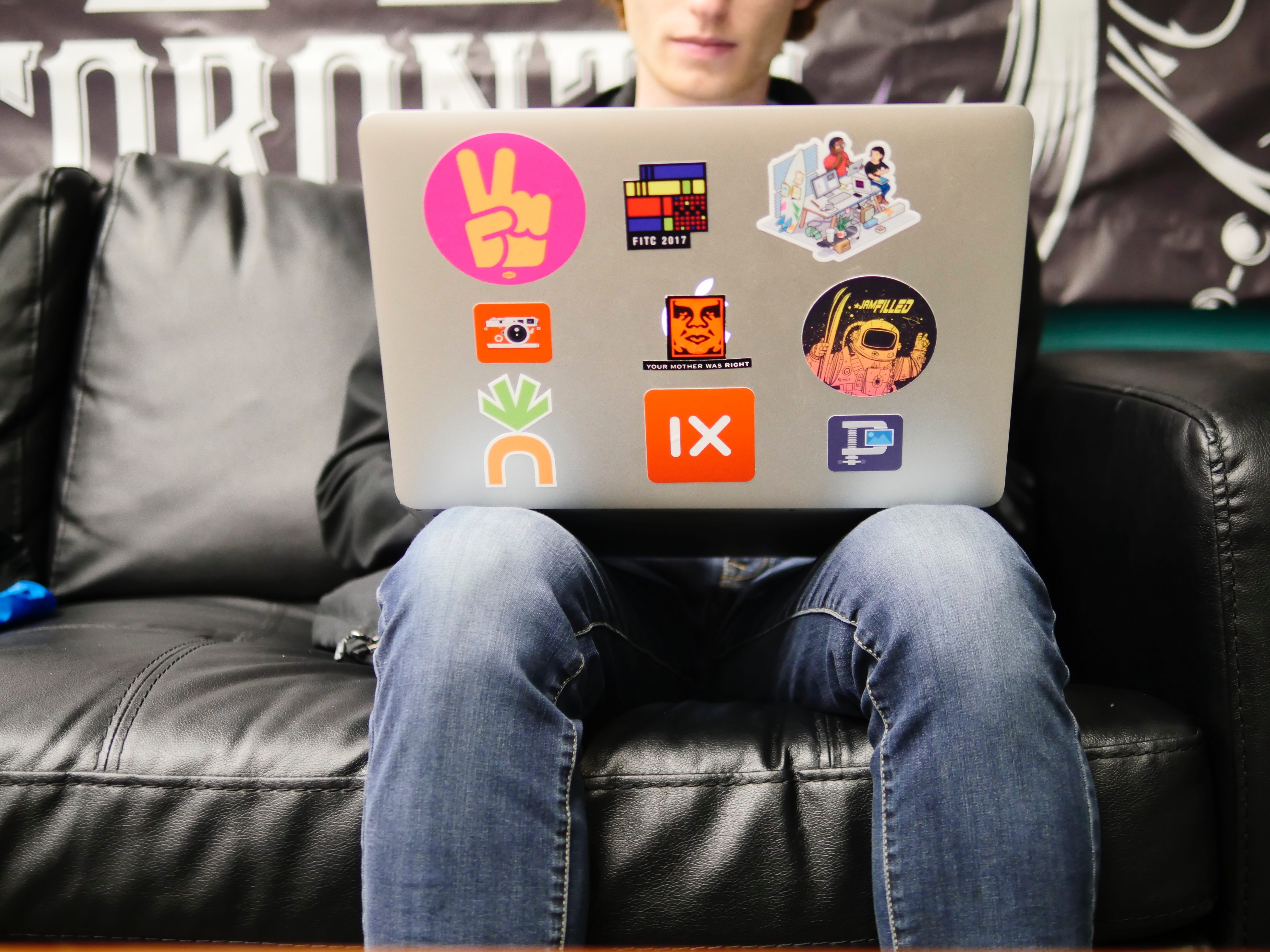 Man using laptop on black leather sofa; image by Imgix, via Unsplash.com.