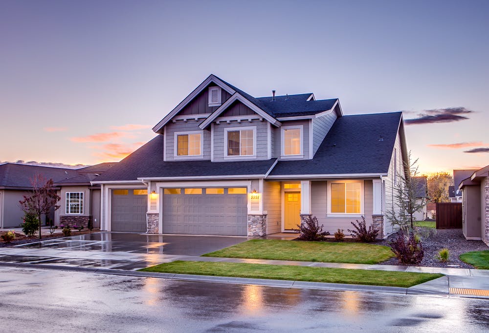 Blue and grey concrete house with attic during twilight; image by Alturas Homes, via Pexels.com.