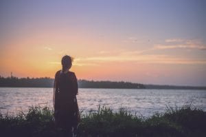 Woman looking at body of water at sunset; image by Praveesh Palakeel, via Unsplash.com.