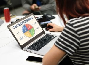 Woman using a laptop to look at a crowdfunding site; image by Rawpixel, via Unsplash.com.