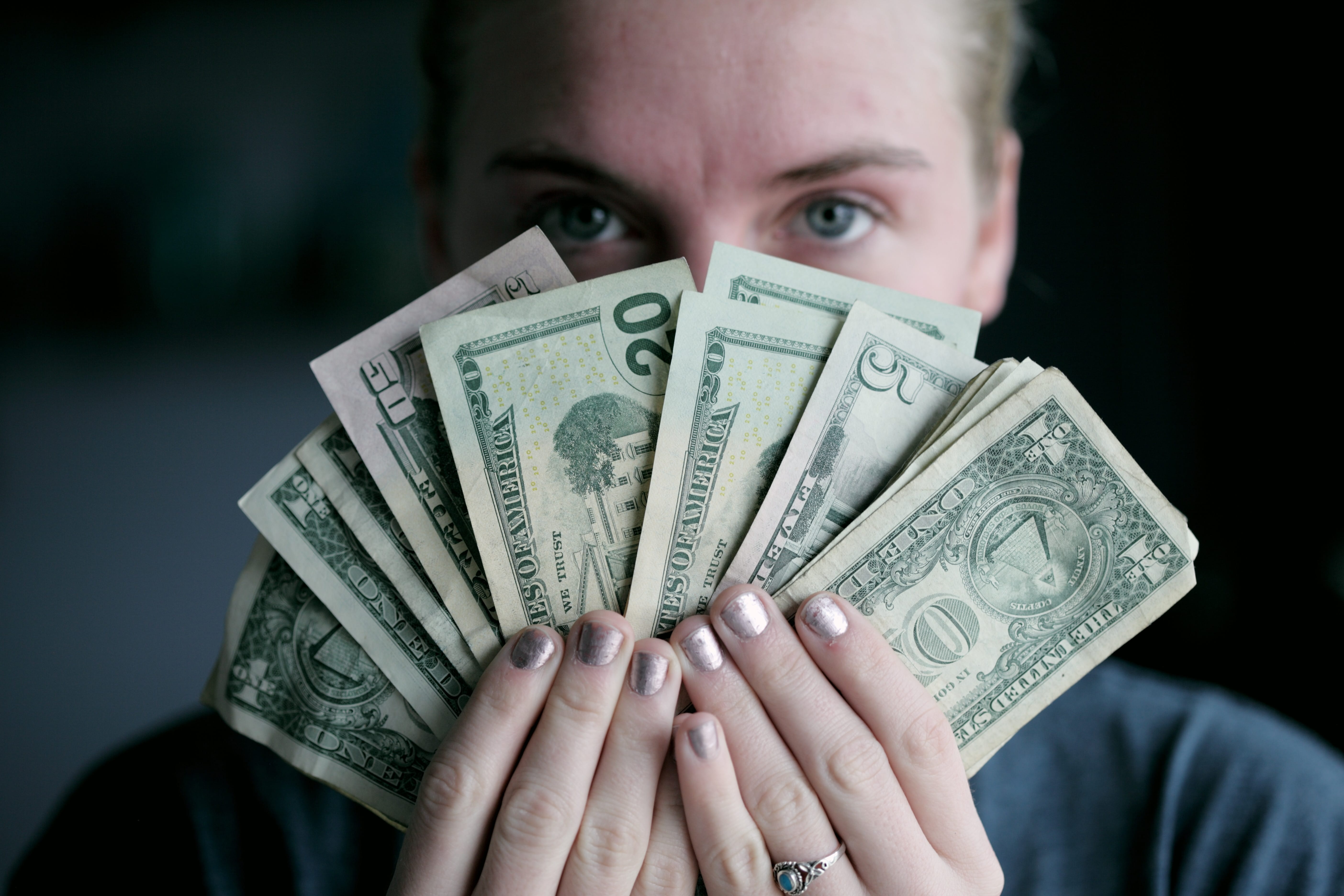 Young woman holding money; image by Sharon McCutcheon, via Unsplash.com.