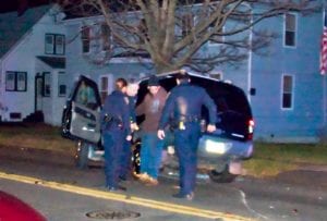 Three uniformed police officers surround a driver being given a sobriety test at night.