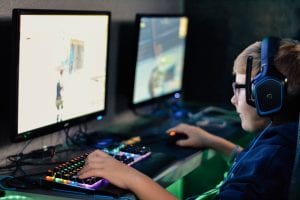 Young boy wearing headphones playing computer game; image by Alex Haney, via unsplash.com.