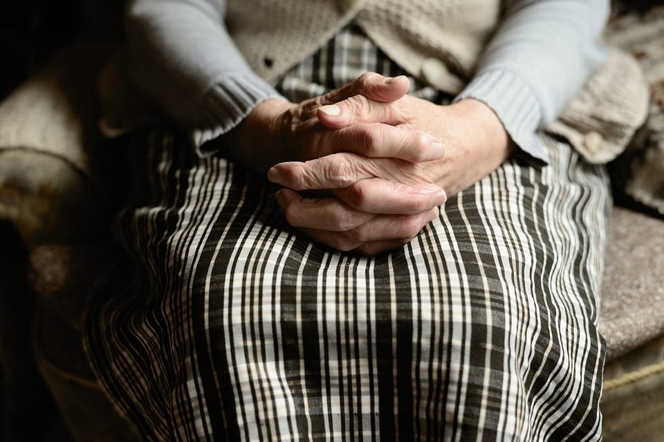 Old woman sitting with folded hands