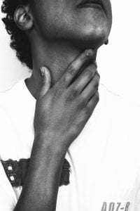 Person with hand on neck, right ear to camera; image by João Silas, via Unsplash.com.