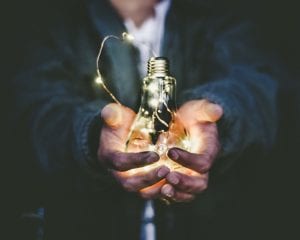 Man holding lit up light bulb; image by Riccardo Annandale, via unsplash.com.