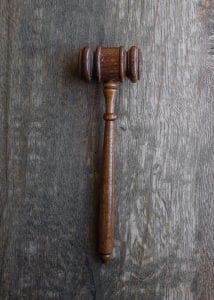 Brown gavel on grey wooden surface; image by Wesley Tingey, via unsplash.com. 