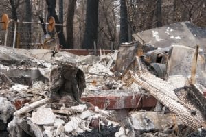 Among the ashes of home destroyed by fire sits a statuette of a guardian angel, grey and charred.