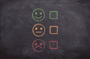 Chalkboard with a smiley face in green, a neutral face in yellow, and a sad face in red, each with check boxes in the corresponding color; image by athree23, via Pixabay.com.