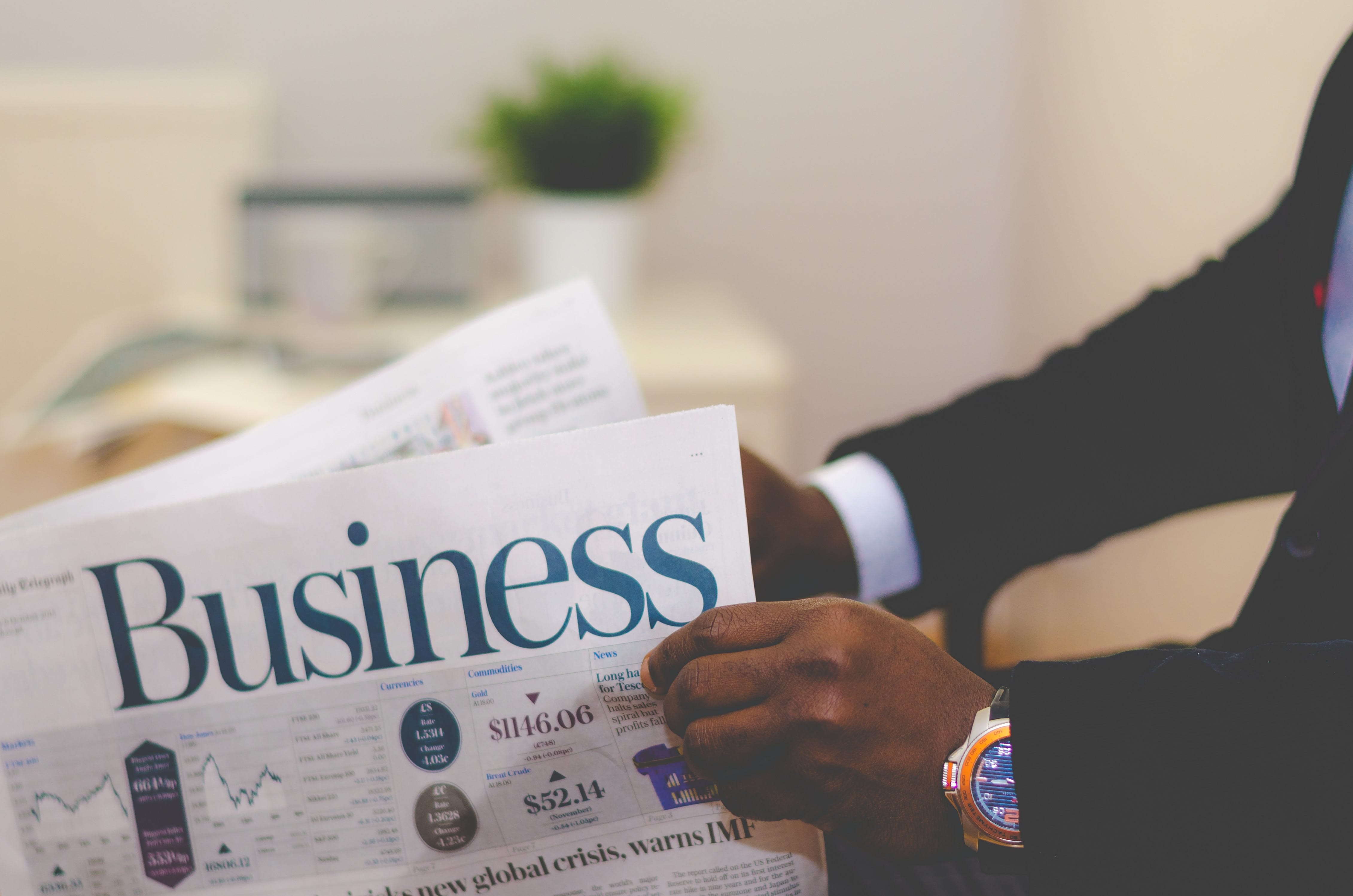 Man in suit reading business newspaper; image by Adeolu Eletu, via Unsplash.com.